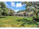 Expansive backyard featuring a screened-in pool area, mature trees, and lush green grass at 8623 Summerville Pl, Orlando, FL 32819