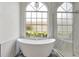Bright bathroom with a soaking tub, glass shower, and large arched window at 8623 Summerville Pl, Orlando, FL 32819