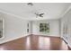 Spacious room with hardwood flooring, ceiling fan, large window, and glass patio doors at 8623 Summerville Pl, Orlando, FL 32819
