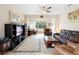 Comfortable living room featuring a leather sofa, ceiling fan, and view into a separate office area at 1028 Salamanca Pl, Davenport, FL 33837