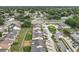An aerial view shows homes with many trees, a road, and many parked cars, under a clear sky at 1113 Woodman Way, Orlando, FL 32818
