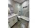 Bathroom featuring gray tile walls, shower, vanity with granite counters and wood-look flooring at 1139 Poppy Ave, Orlando, FL 32811