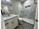 Modern bathroom featuring gray tile, a glass-enclosed shower, and white vanity with updated fixtures at 1139 Poppy Ave, Orlando, FL 32811