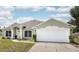 Exterior view of a single-story home with white garage door, manicured landscaping, and well maintained lawn at 1221 N Brickell Dr, Deltona, FL 32725