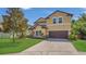 Two-story tan home featuring a well-manicured lawn and attached two-car garage at 15659 Carina Dr, Orlando, FL 32828