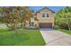 Two-story tan home featuring a well-manicured lawn and attached two-car garage at 15659 Carina Dr, Orlando, FL 32828