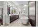 Bright bathroom featuring a soaking tub, double vanity with sleek fixtures, and large mirror at 1820 Englewood Rd, Winter Park, FL 32789