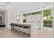 Contemporary kitchen featuring sleek white cabinetry, stone counters with seating, and a wall of windows at 1820 Englewood Rd, Winter Park, FL 32789