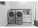 Bright laundry room with stainless steel washer/dryer, white cabinets, sink, and stone tile flooring at 1820 Englewood Rd, Winter Park, FL 32789