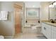 Bright bathroom featuring soaking tub, standing shower and white vanity with black hardware at 2193 County Road 204, Oxford, FL 34484