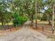 Gated entrance leading to a long, gravel driveway lined with trees and foliage, ensuring privacy at 2193 County Road 204, Oxford, FL 34484
