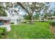 Large backyard with shade trees and lush green lawn, brick home with patio at 2500 Lake Shore Dr, Orlando, FL 32803