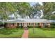 Charming brick home featuring a manicured lawn, brick walkway, and mature trees draped with Spanish moss at 2500 Lake Shore Dr, Orlando, FL 32803