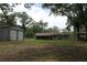 Expansive backyard with large metal shed and covered enclosure, surrounded by lush trees at 26586 Se Highway 42, Umatilla, FL 32784