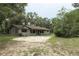 Ranch-style home featuring a long covered front porch, gravel driveway, mature trees, and natural landscaping at 26586 Se Highway 42, Umatilla, FL 32784