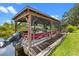 Covered boat house on the water, featuring a red boat and wooden decking at 27714 Lois Dr, Tavares, FL 32778