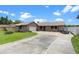 Charming single-story home with a spacious driveway, attached garage, and well-maintained lawn under a sunny blue sky at 27714 Lois Dr, Tavares, FL 32778