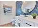 Powder room featuring a blue flower-patterned accent wall, decorative light fixture and a round mirror at 3226 Helen Ave, Orlando, FL 32804