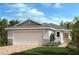 Charming one-story home with a two-car garage, lush landscaping, and a brick driveway at 3281 Rolling Plains Cir, Clermont, FL 34714
