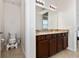 Bright bathroom featuring double sinks, granite countertops, dark wood cabinetry, and a toilet area at 4952 Longmeadow Park St, Orlando, FL 32811