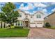 Inviting two-story home with a well-manicured lawn and brick paver driveway at 4952 Longmeadow Park St, Orlando, FL 32811