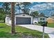 View of the house with gray garage door, mature landscaping and mailbox at 550 Eagle Dr, Daytona Beach, FL 32117