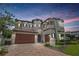 Stunning two-story home with a paver driveway, lush landscaping, and a charming turret entrance at 682 Canopy Estates Dr, Winter Garden, FL 34787