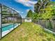Beautiful backyard featuring a large grassy area, privacy fence, and screened-in pool at 720 Meadow St, Sanford, FL 32773