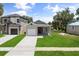 Charming home exterior with manicured lawn, a one-car garage, and a welcoming orange front door, and neighboring home at 817 E Mcdonald Ave, Eustis, FL 32726