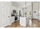 Kitchen with white cabinets, stainless appliances, and island with sink and modern light fixture at 817 E Mcdonald Ave, Eustis, FL 32726