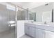 Contemporary bathroom featuring dual sinks, gray vanity, and a glass-enclosed shower for a modern look at 9112 Wildlight Trl, Wildwood, FL 34785