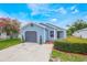 Charming home featuring light blue siding, a gray garage door, landscaped yard with vibrant flowers, and concrete driveway at 104 Yorktown Pl, Sanford, FL 32771