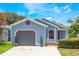 Charming home featuring light blue siding, a gray garage door, landscaped yard with vibrant flowers, and concrete driveway at 104 Yorktown Pl, Sanford, FL 32771