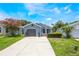 Charming single-story home with light blue siding, gray garage door, landscaped yard, and a concrete driveway at 104 Yorktown Pl, Sanford, FL 32771