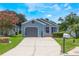 Charming single-story home with light blue siding, gray garage door, landscaped yard, and a concrete driveway at 104 Yorktown Pl, Sanford, FL 32771