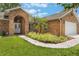Charming brick home featuring an arched entryway, manicured lawn, and lush landscaping at 109 Hunter Point Ct, Debary, FL 32713