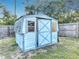 A storage shed with blue painted details and wood trim sitting in the backyard at 1276 Comerwood Dr, Deltona, FL 32738