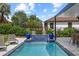 Outdoor covered pool with waterfall feature, lounge chairs, and dining table at 1301 Johns Cove Ln, Oakland, FL 34787