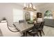 Bright dining room featuring stainless steel table, wood chairs, and modern chandelier lighting at 1364 Augusta National Blvd, Winter Springs, FL 32708
