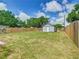 Large backyard featuring a gray shed with white trim, and a wooden fence at 1504 Indiana Ave, St Cloud, FL 34769