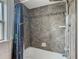 Shower over tub with gray tiles, decorative accents, and a colorful curtain at 1504 Indiana Ave, St Cloud, FL 34769