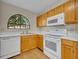 Kitchen with wood cabinets, white appliances, and large arched window at 172 Clear Lake Cir, Sanford, FL 32773