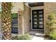 Close-up of the stone exterior with the front door, a modern double door with glass panels at 1781 Pine Ave, Winter Park, FL 32789