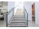 Staircase featuring glass railings leading to the upper level with a view of the modern kitchen at 1781 Pine Ave, Winter Park, FL 32789