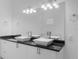 Modern bathroom with dual vessel sinks, black countertops, bright lighting, and a large mirror at 1812 Stoneywood Way, Apopka, FL 32712