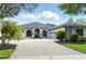 View of a one story home with a well maintained paver driveway, arched windows, and landscaping at 2308 Bur Oak Ct, Oviedo, FL 32766