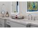 Bright bathroom featuring double sinks, quartz countertops, decorative jars and lighted mirrors with peacock art at 2456 Northumbria Dr, Sanford, FL 32771