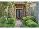 Elegant stone facade entrance with lush landscaping and double glass doors at 2456 Northumbria Dr, Sanford, FL 32771