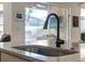 Close-up of a modern kitchen sink with black faucet and granite countertops, offering a view of the backyard at 2456 Northumbria Dr, Sanford, FL 32771