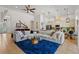 Cozy living room featuring a large sectional sofa, a bright blue rug, and open access to the kitchen and dining areas at 2456 Northumbria Dr, Sanford, FL 32771